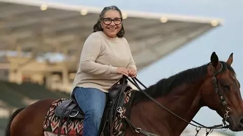 AI Video from prompt: Make the woman on the horse wave at the camera. 