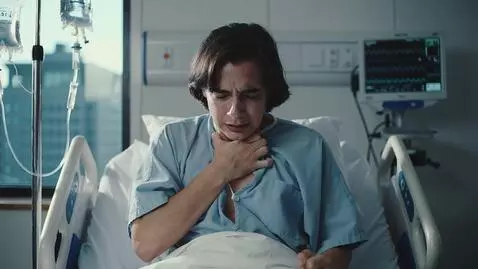 AI Video from prompt: A person sits on a hospital bed, visibly struggl