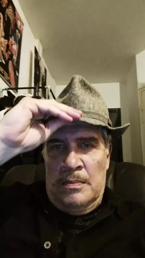 AI Video from prompt: A man puts on a felt hat, stands up, and walks o