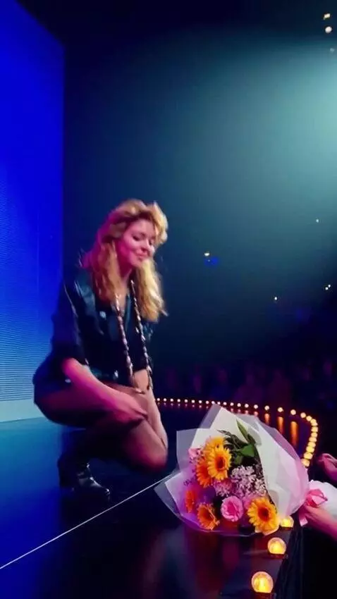 AI Video from prompt: Sandra is on stage in a short dress; she kneels 
