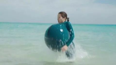 AI Video from prompt: a woman at a beach dives under water. when she r
