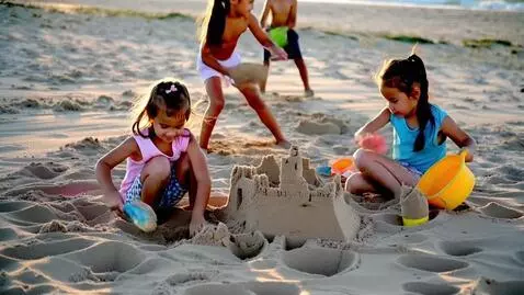 AI Video from prompt: Two beautiful girls playing in the sand at the b