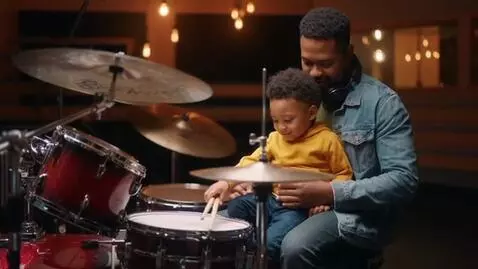 AI Video from prompt: Drummer holding Little boy on his right lap