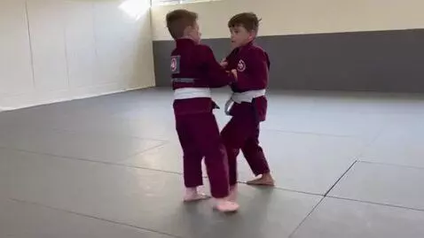 AI Video from prompt: two boys at six years,wearing aubergine bjj jack
