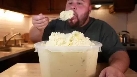 AI Video from prompt: Person eating entire tub of mashed potatoes