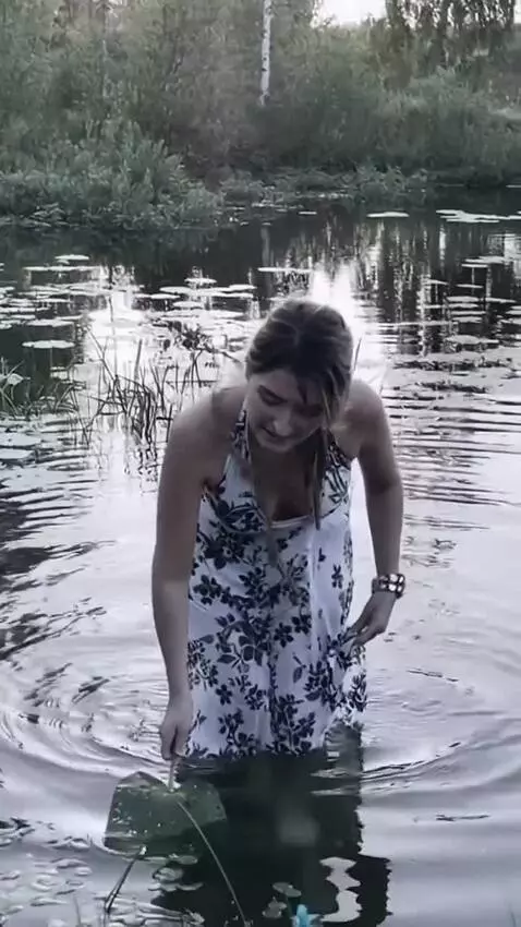 AI Video from prompt: The woman bends low and looks for fish in the wa