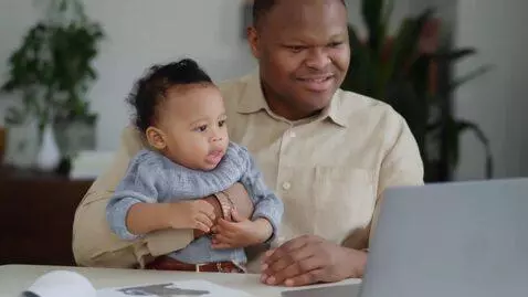 AI Video from prompt: Man using computer with his baby on his lap