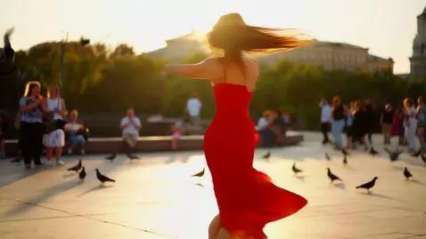 AI Video from prompt: A joyful young woman dances in a sunlit urban pl