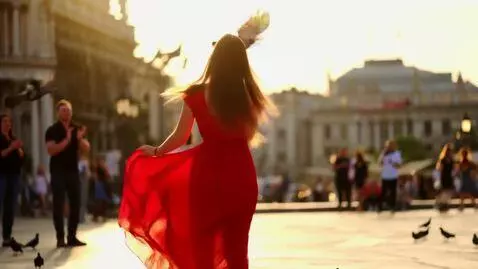 AI Video from prompt: A joyful young woman dances in a sunlit urban pl