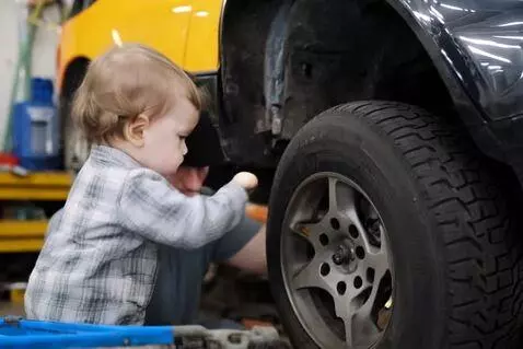 AI Video from prompt: A little baby helping his dad on the mechanic sh
