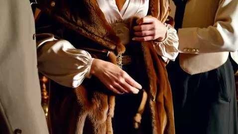 AI Video from prompt: A man gently helps a richly dressed woman remove