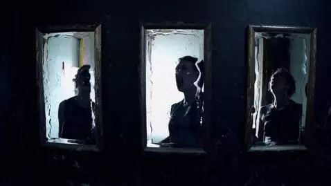 AI Video from prompt: A dark room lined with tall, cracked mirrors. In