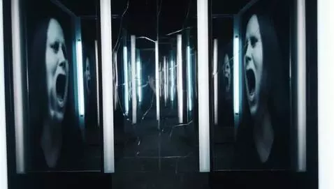 AI Video from prompt: A dark room lined with tall, cracked mirrors. In