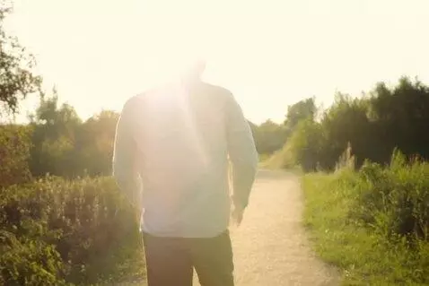 AI Video from prompt: A man walking a path, with light shining over hi