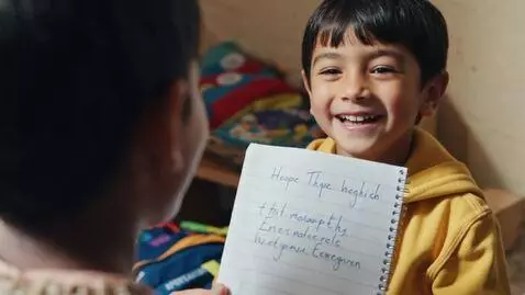 AI Video from prompt: Show a young Afghan child holding a notebook, st