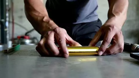 AI Video from prompt: Man crushing gold bars like chocolate