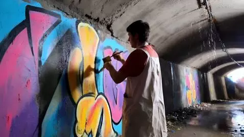 AI Video from prompt: An artist in a canvas apron paints on the wall o