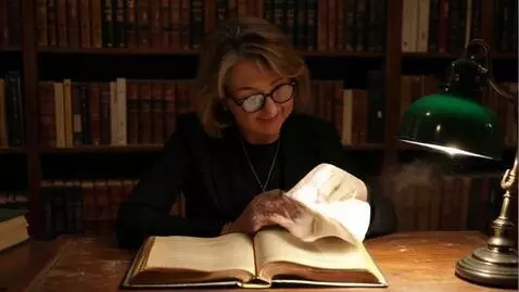 AI Video from prompt: A librarian, wearing glasses on a gold chain, wi