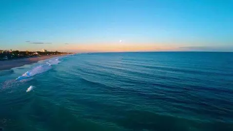 AI Video from prompt: A wide panoramic view of a calm beach at dusk, s