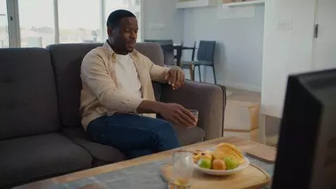 AI Video from prompt: мужчина лежит на диване и смотрит телевизор и пе