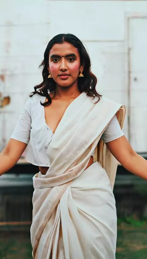 AI Video from prompt: The woman in a white sari transitions from a poi