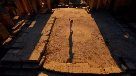 AI Video from prompt: A dancer in silver clothes circles the ruins of 