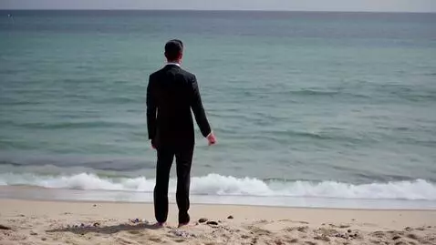 AI Video from prompt: A man in a black suit stands on the shore. He op