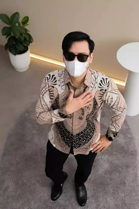 AI Video from prompt: pria ini sedikit manirk kemeja yang dipakainya d