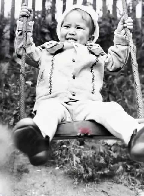 AI Video from prompt: The child is slowly swinging on the swing, laugh