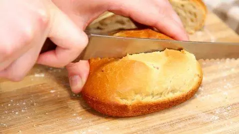 AI Video from prompt: a hand slicing a bread loaf into unseparated hal