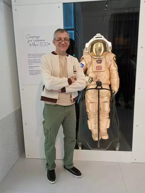 AI Video from prompt: A man poses near an astronaut's spacesuit. The s