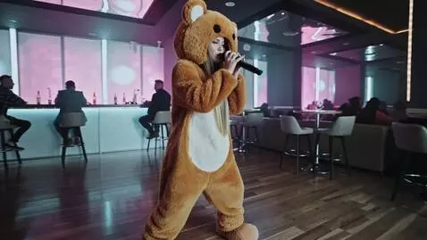 AI Video from prompt: Девушка блондинка в костюме медведя поет в микро