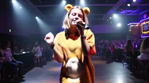 AI Video from prompt: Девушка блондинка в костюме медведя поет в микро