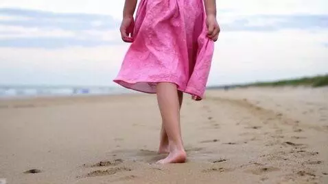 AI Video from prompt: A teen girl walks on the beach wearing a pink kn