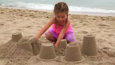AI Video from prompt: a cute little girl building a sandcastle at the 