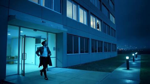 A man exits a high-rise building, walks a few me