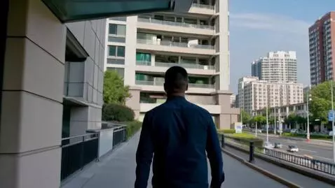 AI Video from prompt: A man exits a high-rise building, walks a few me