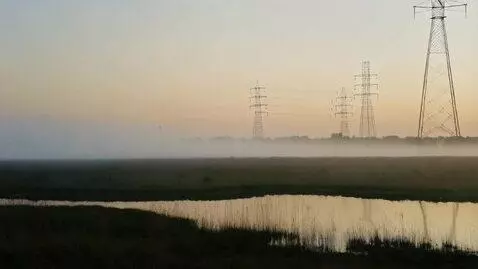 AI Video from prompt: Mist rolling over shallow ponds, electric towers