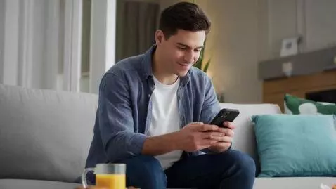 AI Video from prompt: A guy is sitting on the couch. He gets a notific