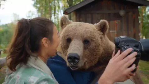 AI Video from prompt: Bear which is trained and takes photo with peopl