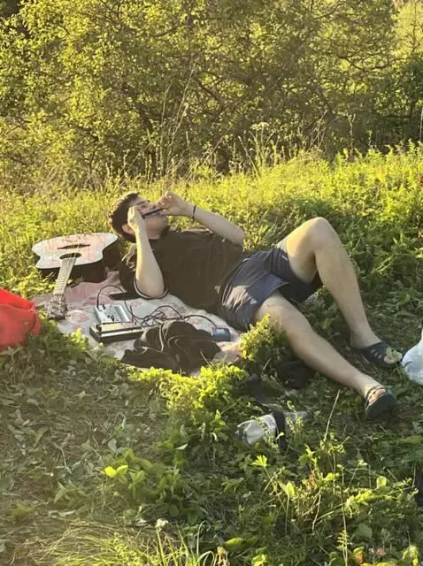 AI Video from prompt: A guy lean on grass and play harmonica