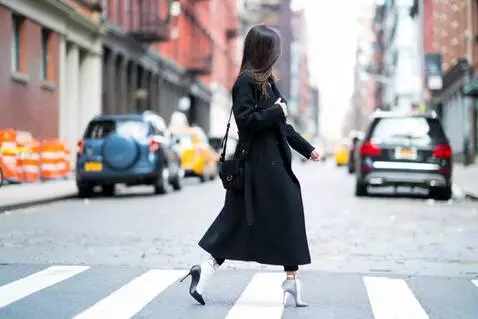 AI Video from prompt: A young woman wearing a black coat and jeans wal