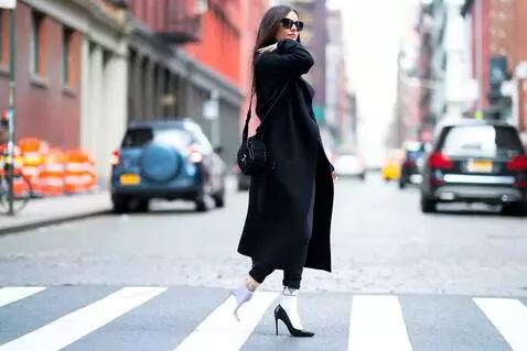 AI Video from prompt: A young woman wearing a black coat and jeans wal