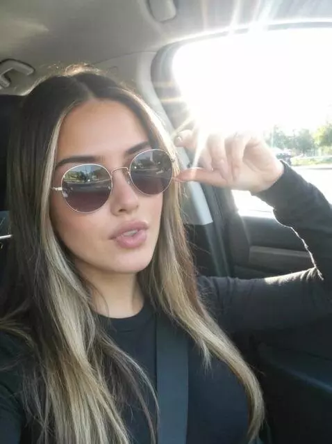 AI Video from prompt: Adjusting sunglasses, parting lips subtly