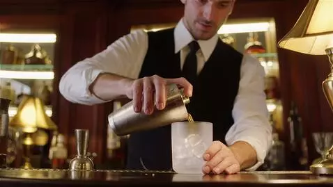 AI Video from prompt: In a cozy, dimly lit bar, a bartender in a perfe