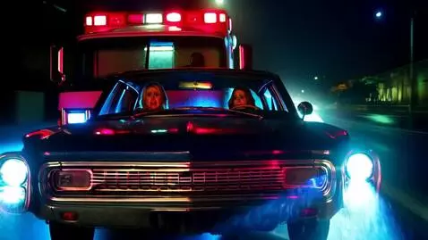 AI Video from prompt: Driving their car, they follow an ambulance as t