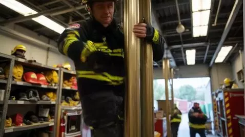AI Video from prompt: A firefighter climbs down a pole inside the fire