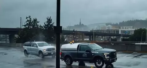 AI Video from prompt: Two pickups drive through the parking lot in clo