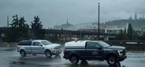 AI Video from prompt: Two pickups drive through the parking lot in clo