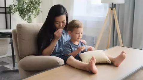 AI Video from prompt: Mom sits on her chair and her son licks her toes